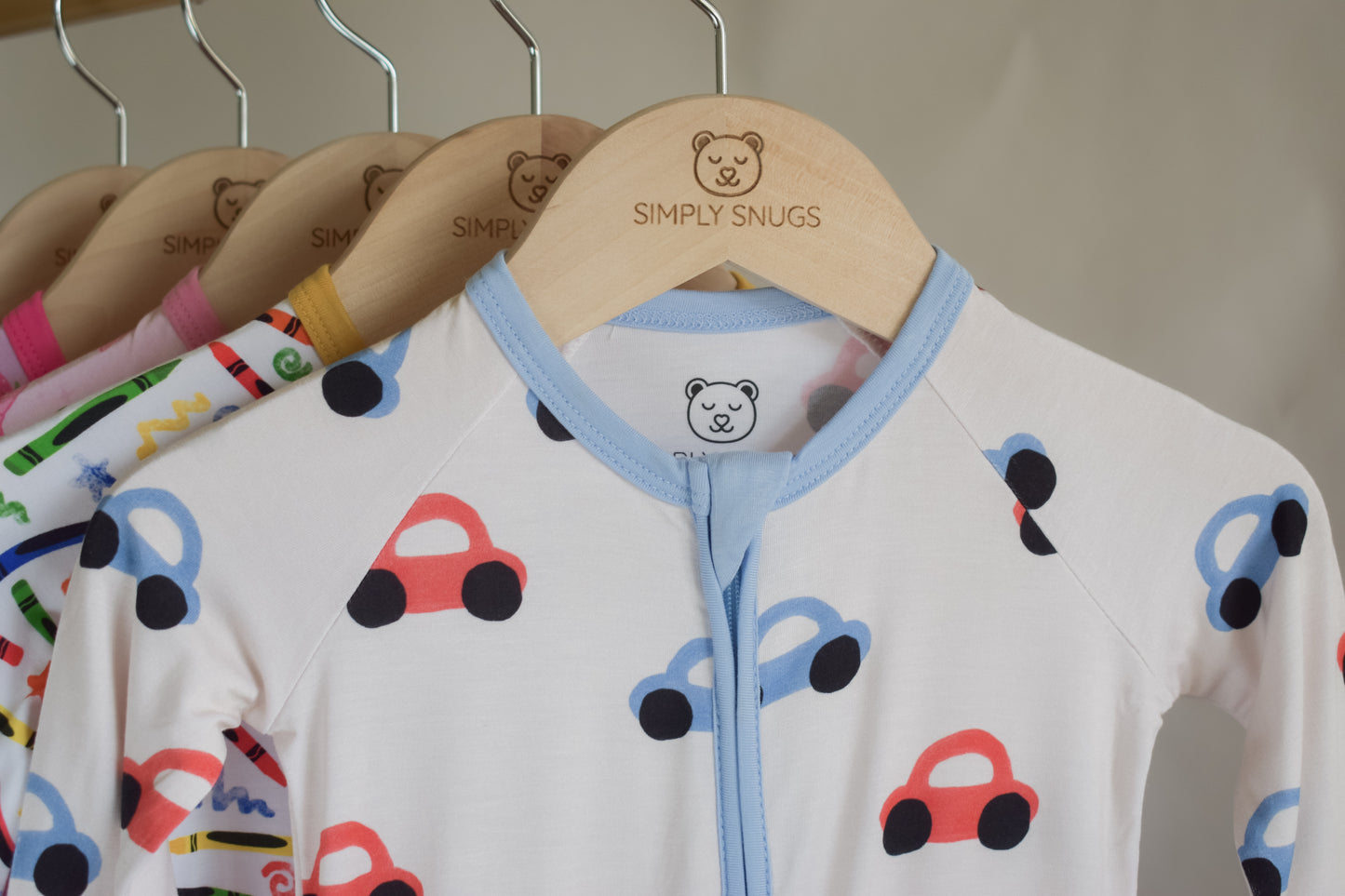 Children's pajama with car pattern on hanger with 'Simply Snugs' brand.