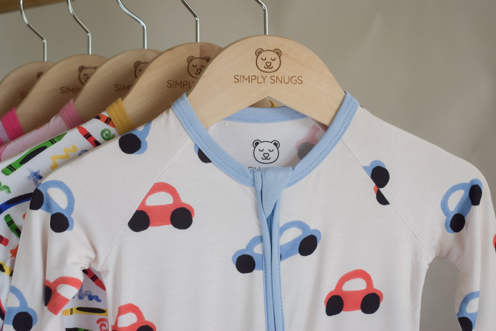Children's pajama with car pattern on hanger with 'Simply Snugs' brand.